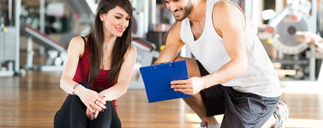 Ein Mann und eine Frau sitzen in einem Fitnessstudio auf dem Boden.