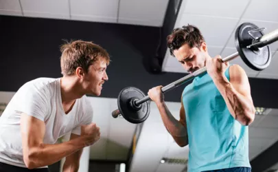 Zwei Männer heben Hanteln in einem Fitnessstudio.