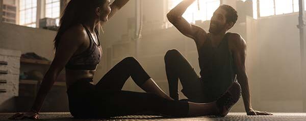 Ein Mann und eine Frau machen Yoga in einem Fitnessstudio.