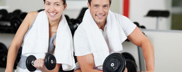 Lächelnde Frau und Mann beim Bizepscurls-Training mit Kurzhanteln im Fitnessstudio.