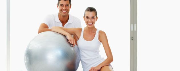 Ein Mann und eine Frau posieren mit einem Gymnastikball.