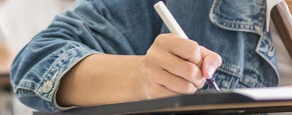 Eine Person schreibt mit einem Stift in ein Notizbuch.
