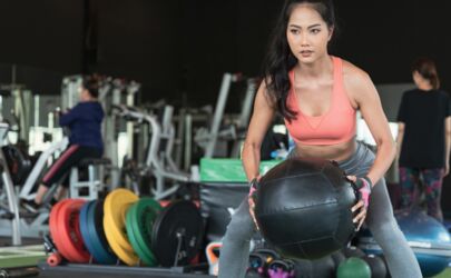 Eine Frau in einem Fitnessstudio hält einen Gymnastikball in der Hand.