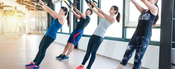 Eine Gruppe von Menschen macht Trx-Übungen in einem Fitnessstudio.