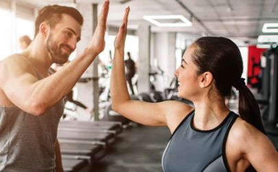 Ein Mann und eine Frau geben sich in einem Fitnessstudio gegenseitig ein High Five.