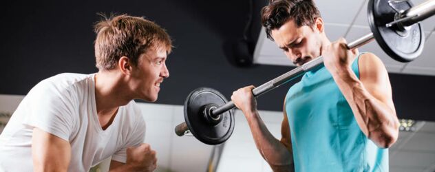 Zwei Männer heben Hanteln in einem Fitnessstudio.