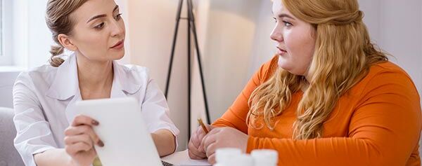 Zwei Frauen sitzen an einem Tisch und unterhalten sich mit einem Arzt.