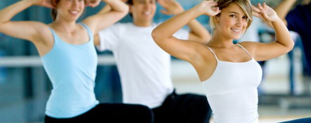 Eine Gruppe von Menschen macht Yoga in einem Fitnessstudio.