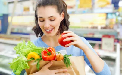Eine Frau hält eine Papiertüte voller Gemüse in einem Lebensmittelgeschäft.