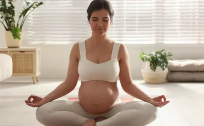Junge schwangere Frau übt Yoga zu Hause