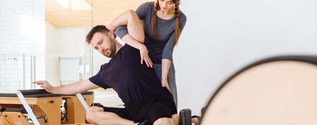 Ein Mann und eine Frau machen Pilates in einem Fitnessstudio.