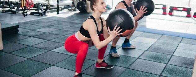 eine Frau und ein Mann machen Übung mit Medizinball im Fitness Studio