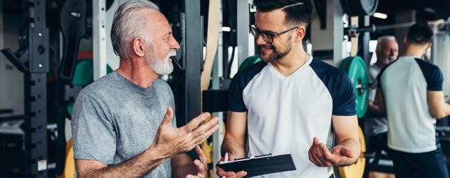 Ein Mann spricht mit einem Mann in einem Fitnessstudio.