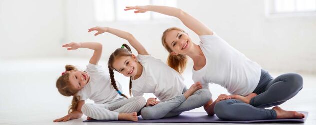 Drei junge Mädchen machen Yoga auf einer Matte.