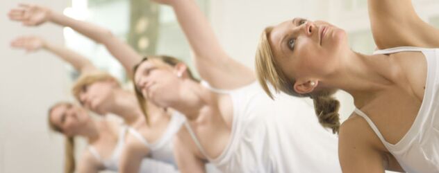 Eine Gruppe von Frauen macht Yoga in einem Raum.