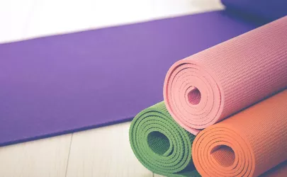 Vier Yogamatten in unterschiedlichen Farben liegen auf dem Boden