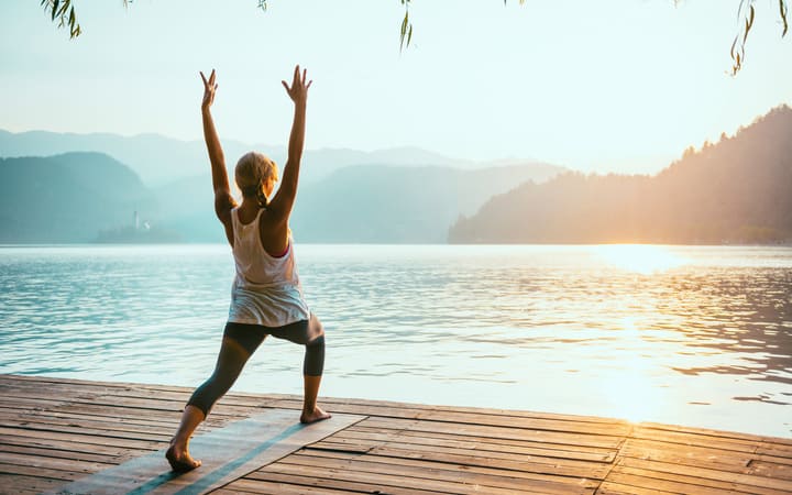 Frau in der Yoga Stehhaltung des Sonnengrußes vor dem Sonnenaufgang