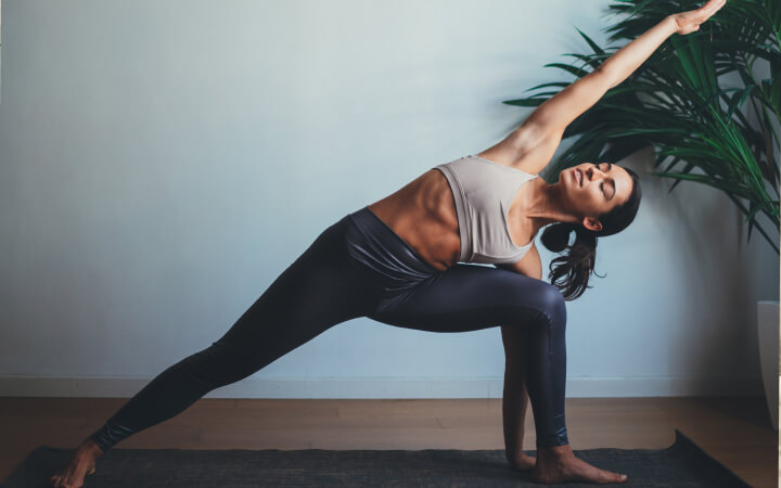 Frau praktiziert Yoga Übung gestreckter Winkel. Die Drehhaltung im Ausfallschritt dient sowohl der Dehnung als auch Kräftigung des Körpers