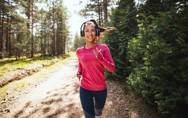 Frau joggt motiviert in der Natur mit Kopfhörern.